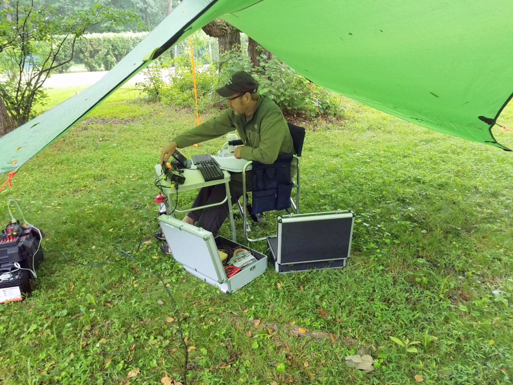 WA8YIH operating underneath his tarp shelter at W3BQC Field Day 2018. At night, the tarp sheltered the hammock he slept in.