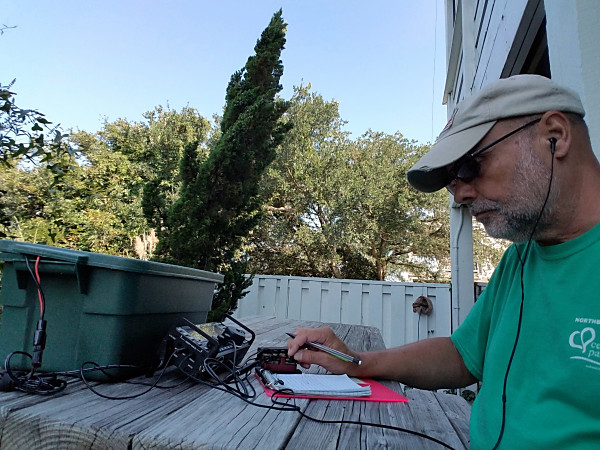 Operating from the picnic table. Above my arm, in the background, you can see the feedpoint for the inverted L antenna. My 9:1 UNUN is wrapped up for weather protection.