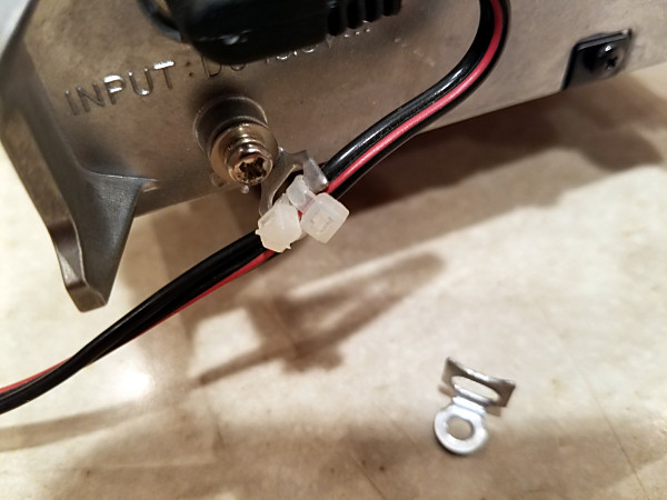 Close-up of the right-angle lug attached to the ground stud. Two small nylon tie-wraps secure the power cord to the lug. An unused lug is shown in the bottom of the picture.