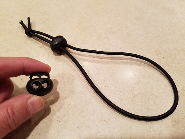 A completed bungee cable tie, along with one of the two-hole cord locks I used.