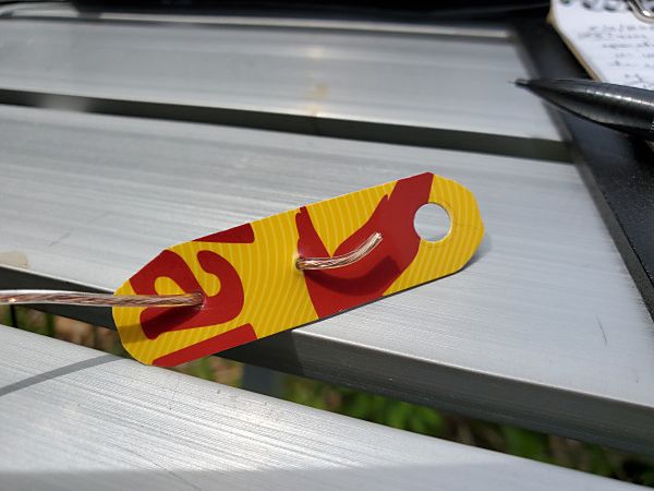 An improvised end insulator made from an old gift card. I used this so I could shorten the wire, if needed, by folding it back on itself.